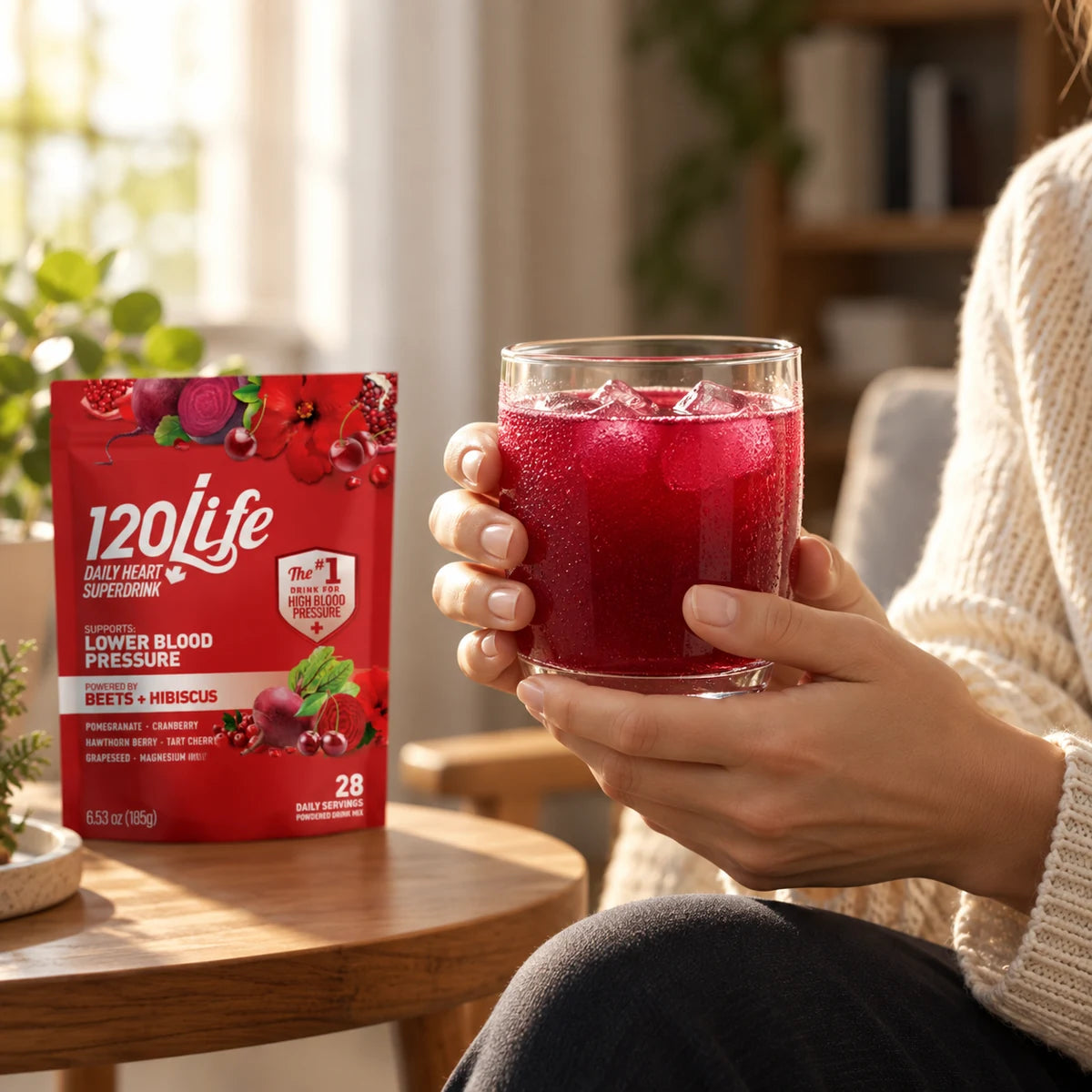 A cold glass of 120/Life held by a window, with the powder pouch nearby