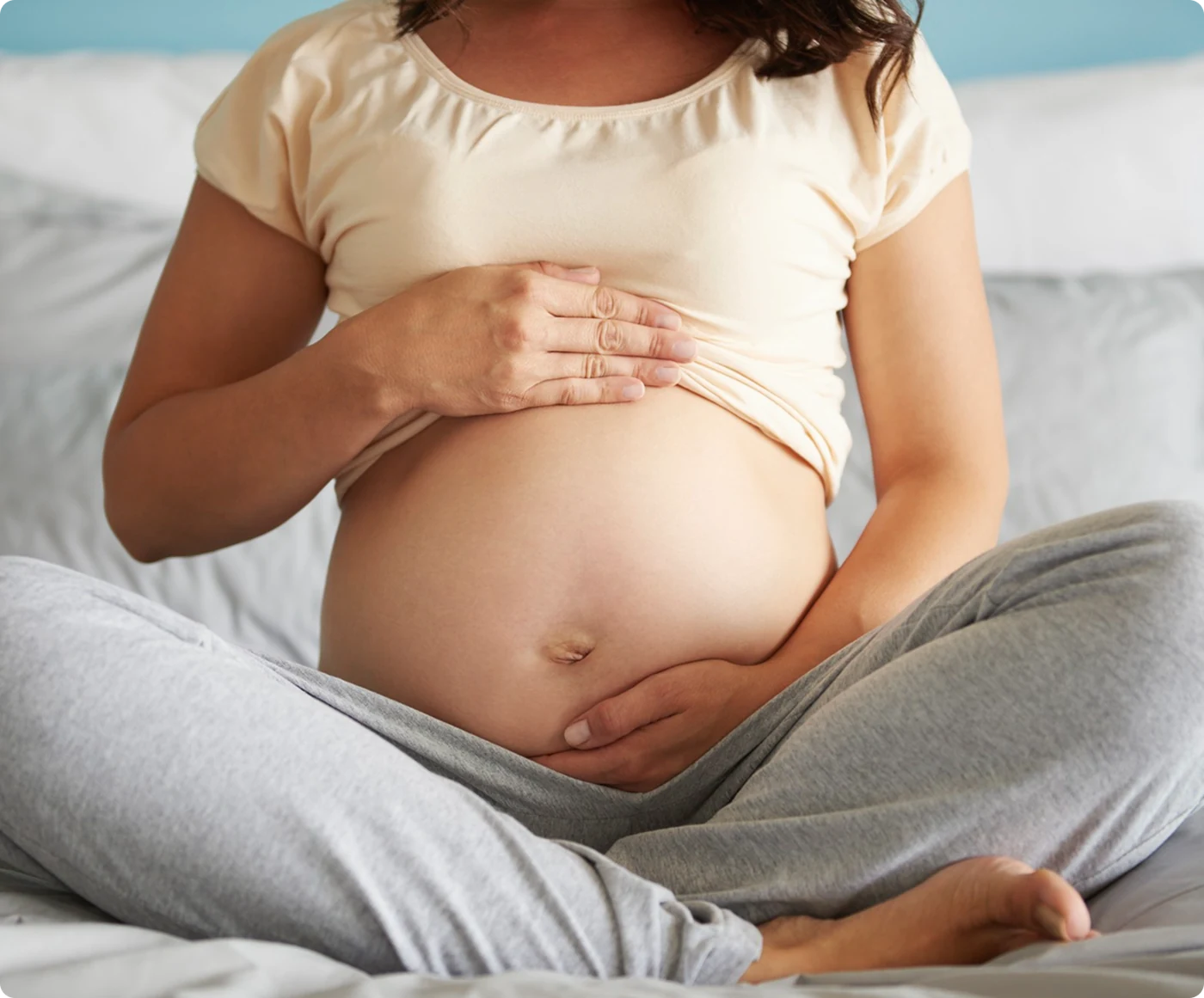 A pregnant woman resting her hands on her belly